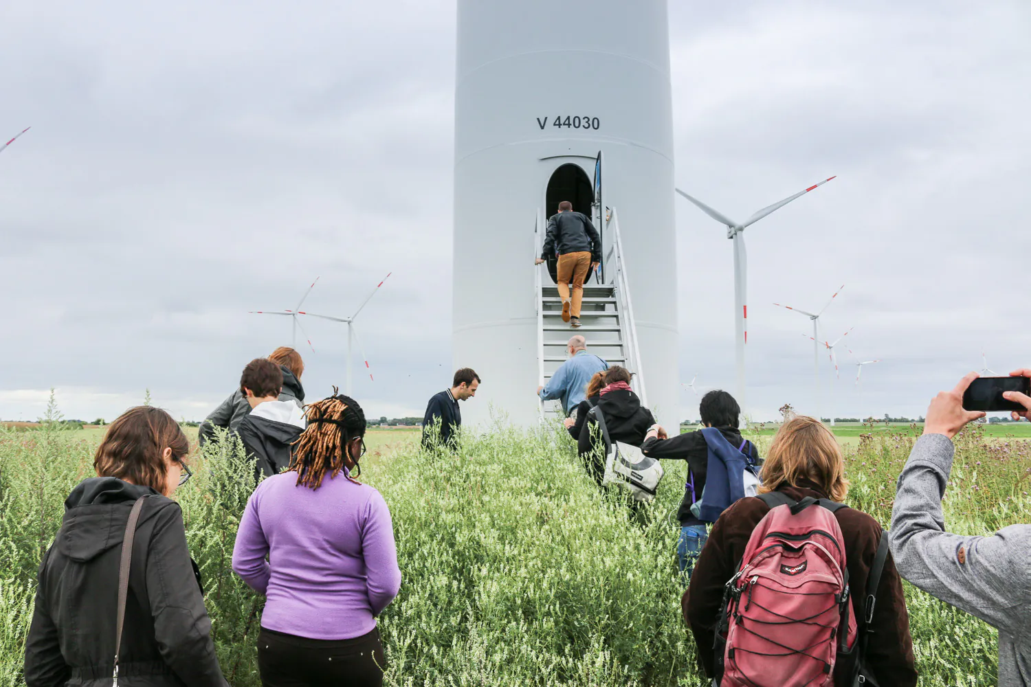 Teilnehmende der IKEM Summer Academy besichtigen eine Windkraftanlage im Feld