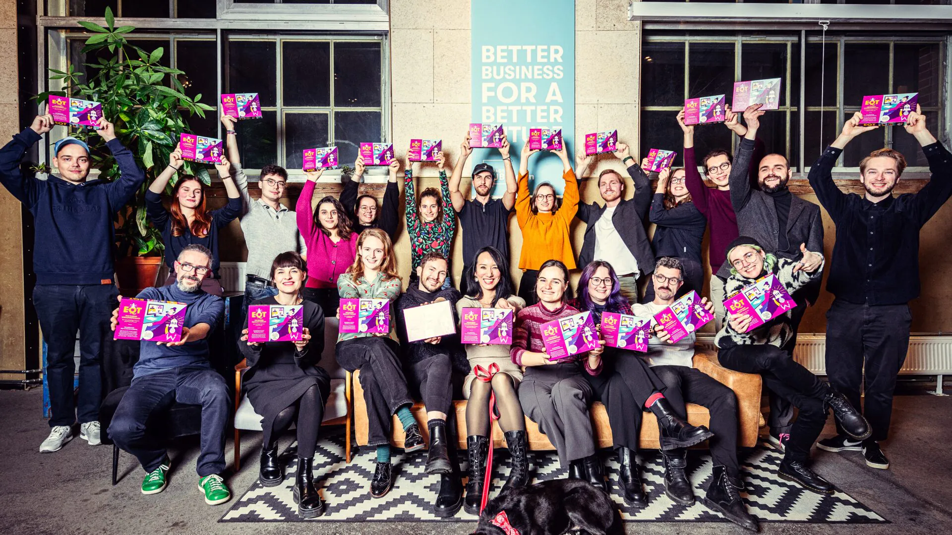 Gruppenfoto: Viele Teilnehmende halten pinkviolette Schachteln des EQT-Toolkits in die Höhe