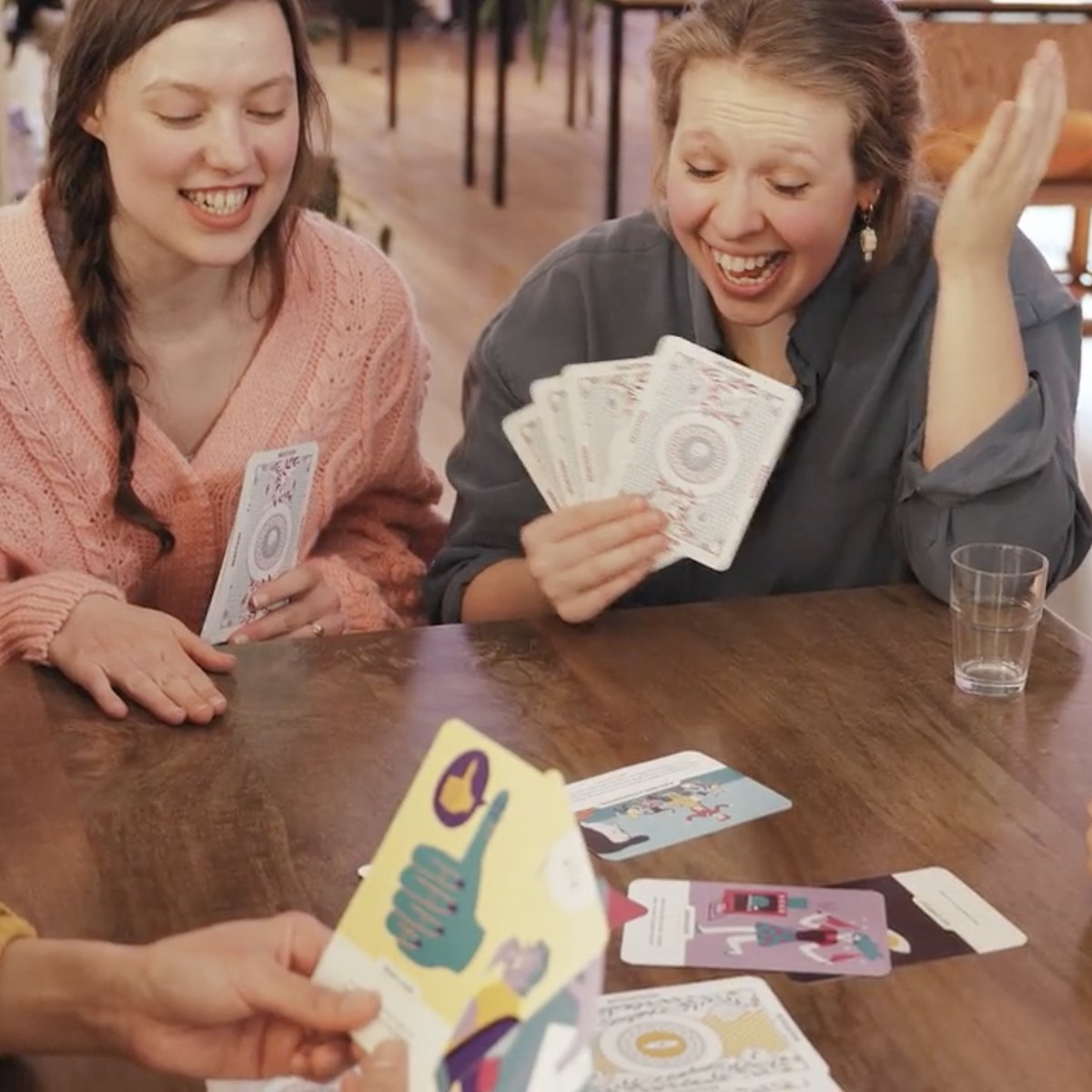 Two women laughing and talking while playing the EQT card game